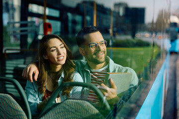 Happy man and is girlfriend traveling by city bus and looking through window.