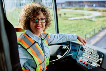 Happy female bus driver at work looking at camera. - obrazy, fototapety, plakaty