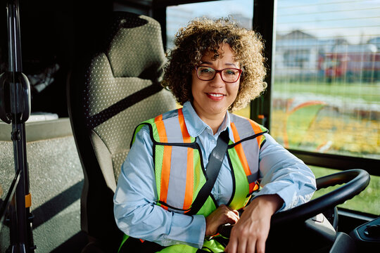 Happy female driver in public bus looking at camera.