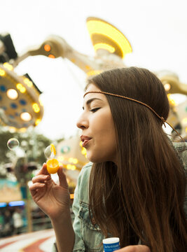 Close-up portrait of teenage girl blowing bubbles at amusement park, Germany