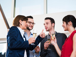 Mature businesswoman toasting group of young business people with glasses of champagne, Germany