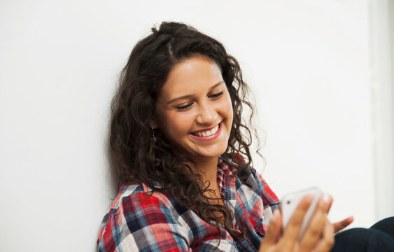 Close-up portrait of teenage girl looking at cell phone and smiling, Germany