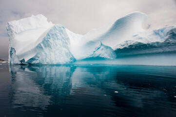 Abstract shape of an iceberg with blue ice shadows and dark, turquoise water of the Southern Ocean at Cierva Cove in Hughes Bay; Antarctic Peninsula, Antarctica