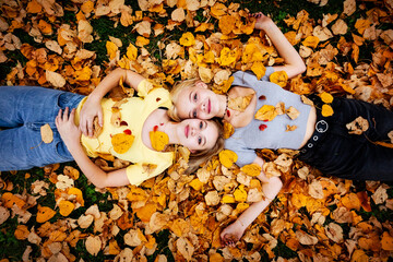 Portrait of two teenage girls laying on the ground in the fallen leaves and looking up at the camera on a warm fall day; St. Albert, Alberta, Canada.