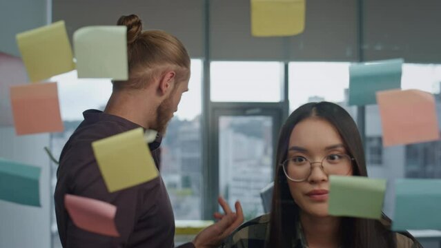 Nervous team arguing at stickers wall office closeup. Angry man tearing notes