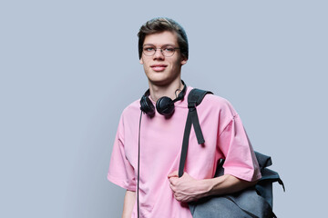 Trendy young male hipster in pink t-shirt on gray studio background