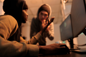 Diverse hackers talking about computer server hacking, committing cyberattack and cyberterrorism. Thieves in hoodies cracking password, scammers planting malicious software at night time.
