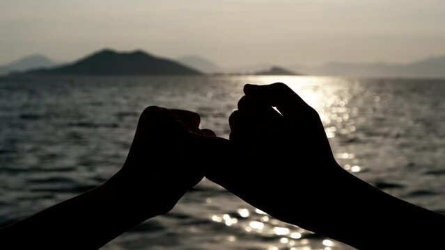 Reconciliation on the fingers. Silhouette of hands holding pinkies.