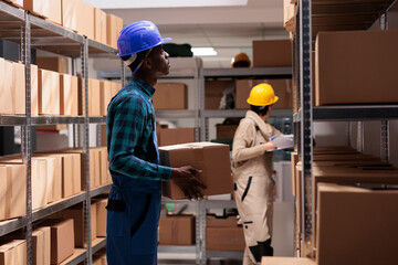 Factory shipping department employee standing with cardboard box, managing logistics and distribution. African american storehouse worker holding customer order ready for delivery