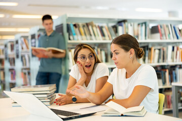 Portrait of cheerful female friends together in public library