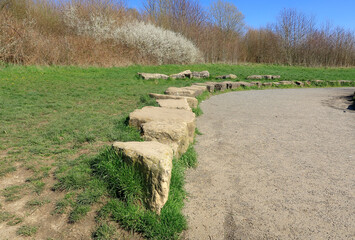 A small wall of stones alongside a footpath through the North Kent countryside