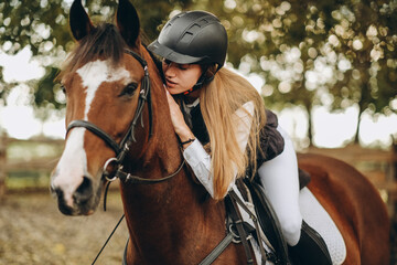 Obraz premium A young woman jockey lies on her horse and hugs her.