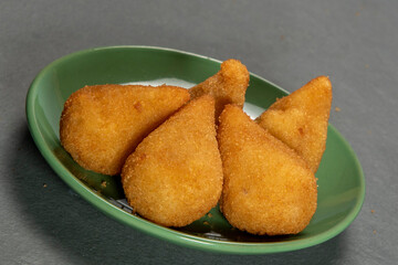 traditional fried coxinha in plate on slate background, popular brazilian snack