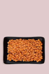 Red lentil in bowl isolated on pink background. Top view