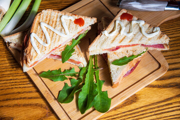 Sandwich with ham, cheese, tomatoes, lettuce, and toasted bread...homemade sandwiches on wooden background...