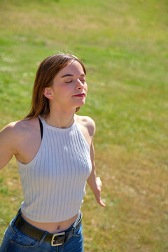 Young Girl Standing With Her Arms Outstretched Behind Her Breathing Deeply With Her Eyes Closed