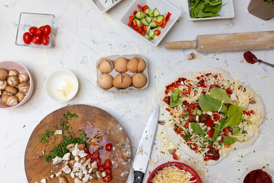 Close up of food ingredients and pizza on countertop in kitchen