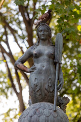 Obraz premium 11 AUG 2022: Milan, Italy - A statue of a mermaid with a sword and pigeon on it