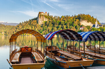 Small boats on a lake with a castle on top of a mountain in the background.  Sunset hour.