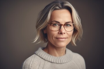 Fototapeta premium Portrait of a beautiful middle-aged woman in glasses and a sweater.