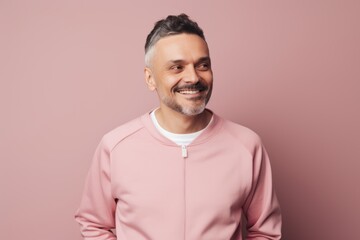 Obraz premium smiling middle aged man in pink hoodie looking at camera isolated on pink