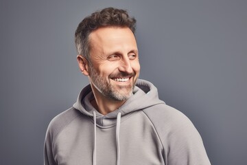 Fototapeta premium Portrait of a smiling mature man in hoodie on grey background