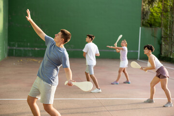Caucasian teenage boy in sportswear playing paleta fronton on outdoor court - obrazy, fototapety, plakaty