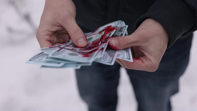 Illegal earnings, Criminal wealth, Counting cash. Hands of a man are reckoning up dollars smeared with blood.