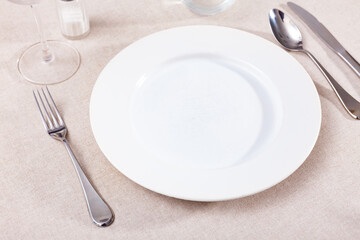 Plate with silverware, nothing served. Empty crockery on table.