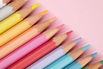 Colored pencils of pastel colors on a pink background. Multi-colored pastel pencils.