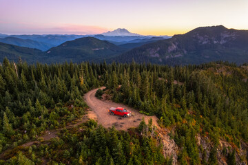 Drone shot of a pickup truck in front of volcanic mountain. Mount Rainier in the background. A perfect spot for camping off the grid. Copy space - obrazy, fototapety, plakaty
