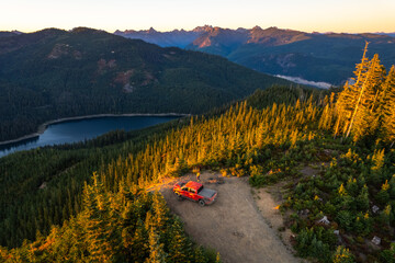 Drone shot of a pickup truck in front of volcanic mountain. Mount Rainier in the background. A...