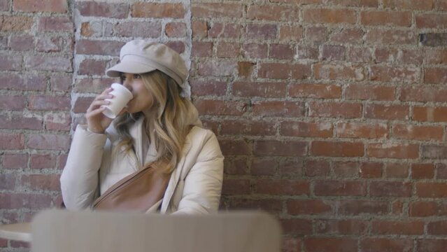 A pretty woman is dressed for the cold and drinking a hot beverage