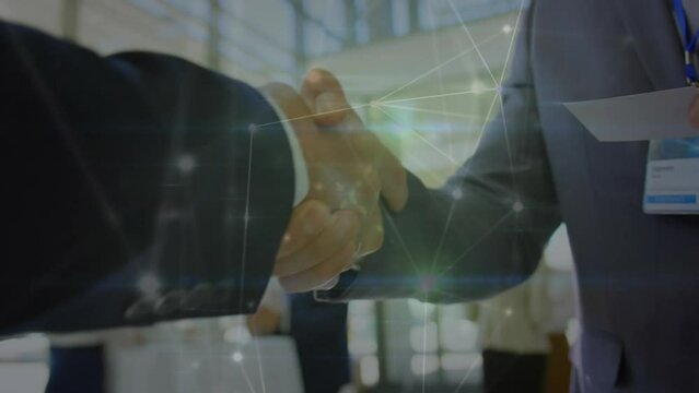 Animation of network of connections over mid section of two businessmen shaking hands at office