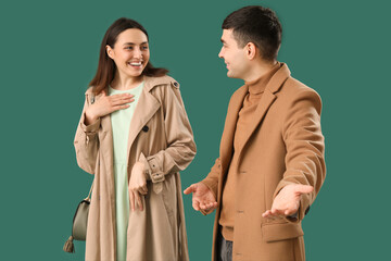 Young man letting beautiful woman go first on green background