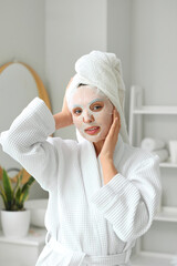 Young woman with sheet mask in bathroom