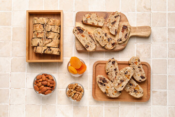 Fototapeta na wymiar Composition with tasty biscotti cookies, nuts and dried apricots on light tile background
