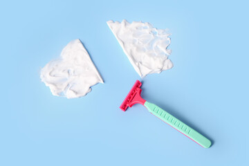 Safety razor and shaving foam on color background