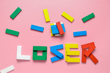 Word LOOSER made of colorful blocks on pink background