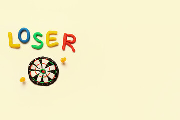 Word LOSER with dartboard made of plasticine and pins on white background