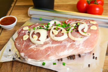 Aluminium foil roll with piece of raw meat and spices on wooden table, closeup