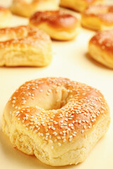 Tasty bagels with sesame seeds on beige background, closeup