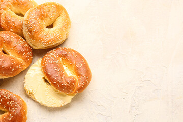 Tasty bagels with sesame and cream cheese on light background