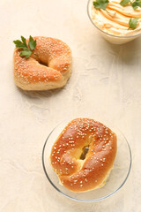 Plate with tasty bagels on light background