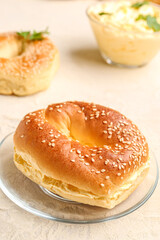 Plate with tasty bagels on light background