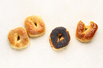 Tasty bagels with sesame and poppy seeds on light background