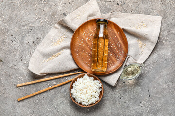 Composition with boiled rice, bottle of vinegar and chopsticks on grunge background