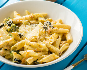 A white plate of Chicken pasta with vegetables
