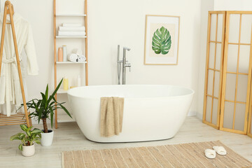 Stylish bathroom interior with beautiful tub and houseplants