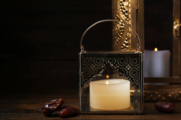 Muslim lamps with burning candles and dates on dark wooden background